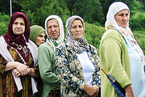 Grieving women pass by the stone marker at the Potocari memorial site for victims of the 1995 Srebrenica massacre, in which 8,000 Bosnian Muslim men and boys were massacred by Serb forces - photo by Adam Jones